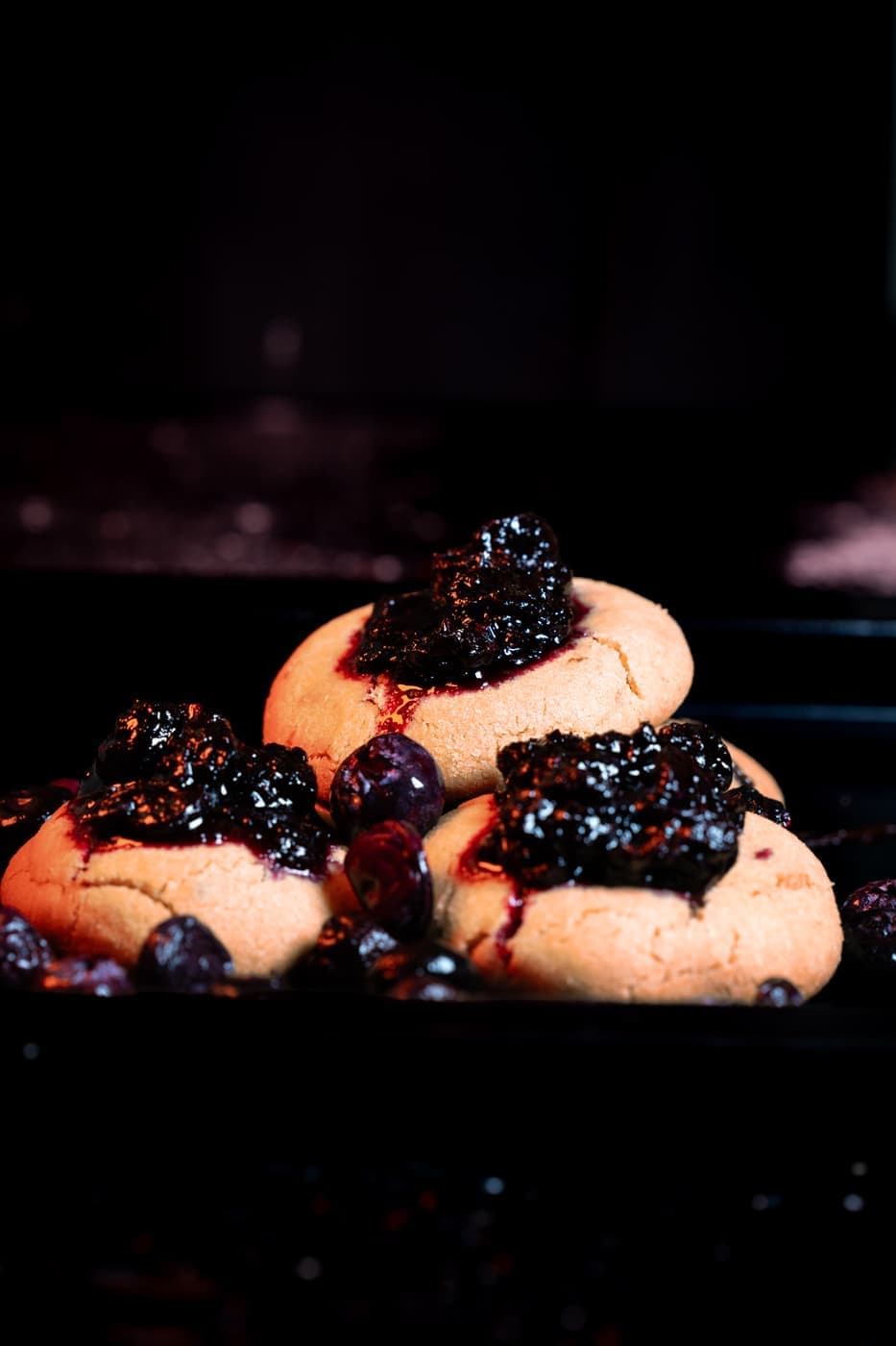 Blueberry Cookies on a rack, jammy blueberry pooled in the centre of each.