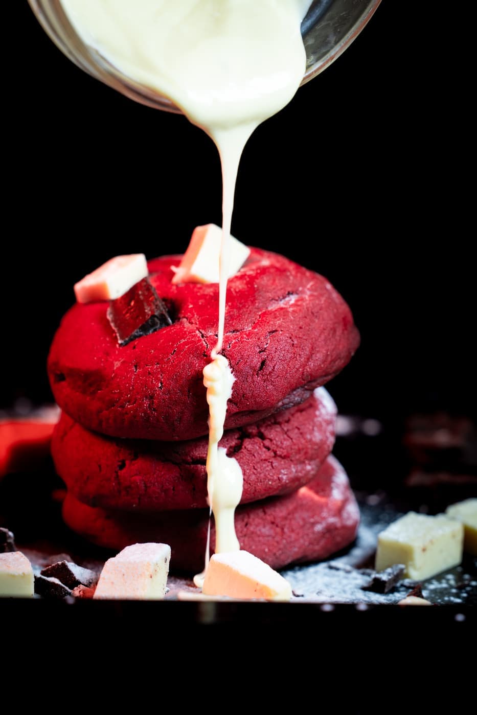 Red Velvet Cookies stacked, white chocolate poured over the top.