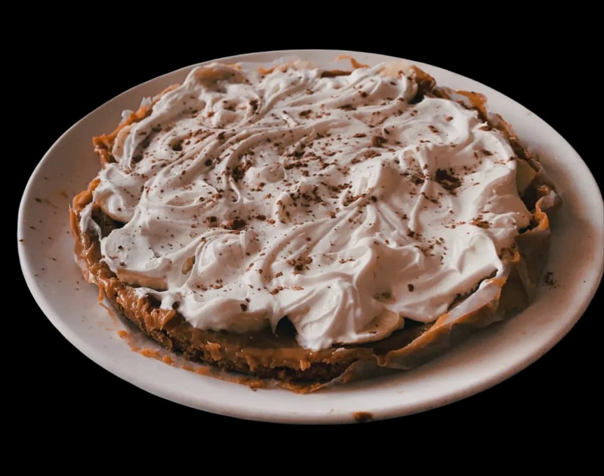 A banoffee pie topped with swirls of cream and grated chocolate.