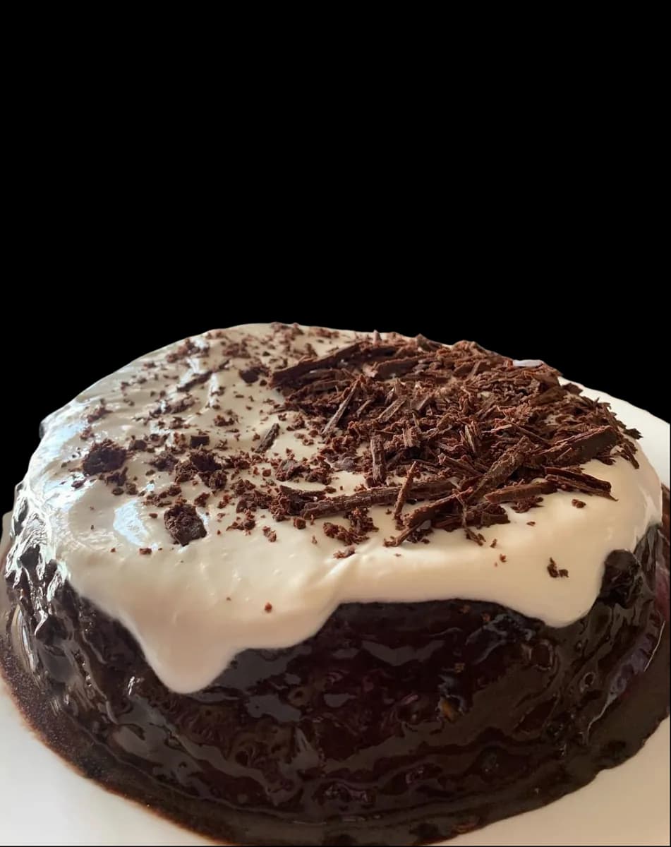 A chocolate cake under white cream and dark chocolate shavings.