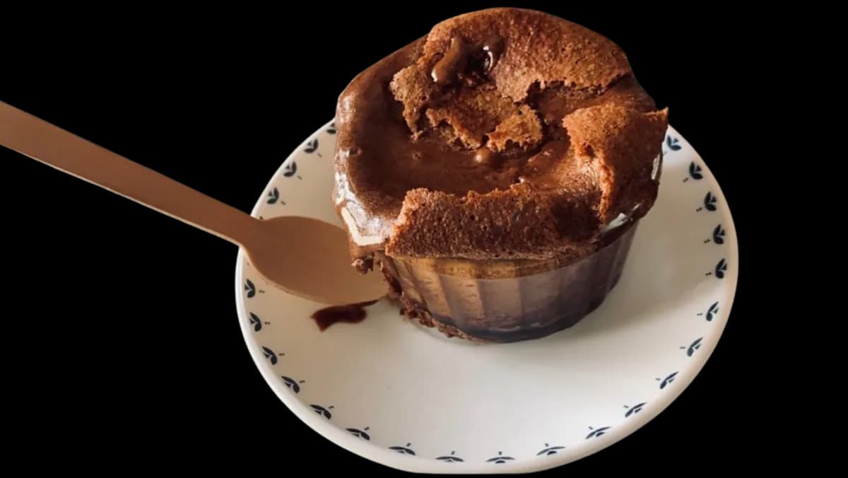 A chocolate lava cake on a patterned plate, spoon at its edge.