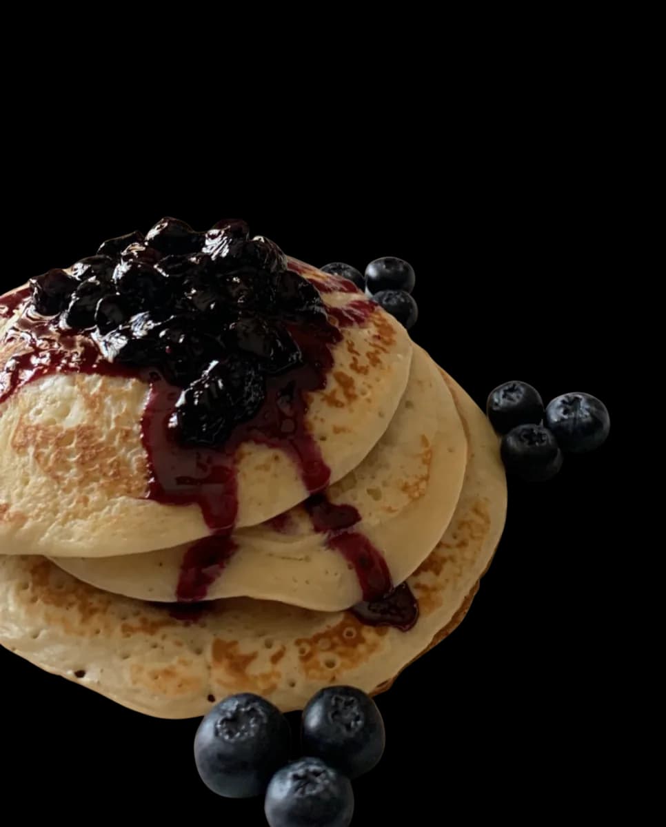 A stack of pancakes under blueberry compote.